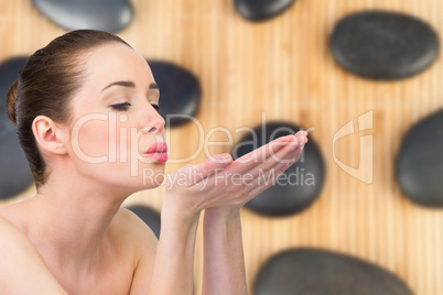 Composite image of beautiful brunette blowing over hands