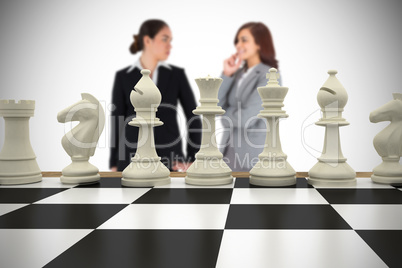 Composite image of businesswomen and chess pieces