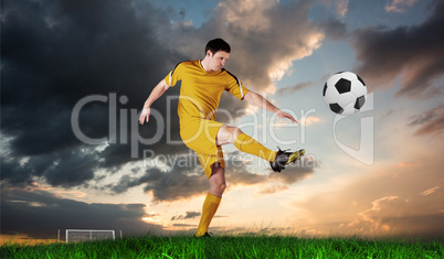 Composite image of football player in yellow kicking