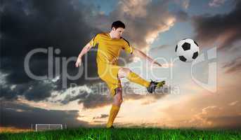 Composite image of football player in yellow kicking