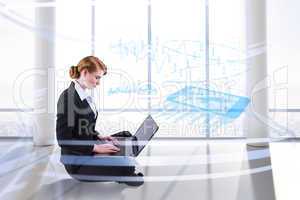 Composite image of redhead businesswoman using her laptop