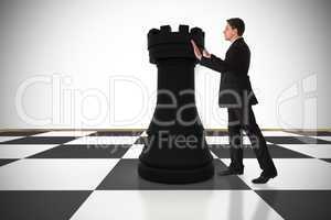 Composite image of businessman in suit pushing chess piece