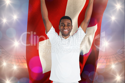 Composite image of excited handsome football fan cheering holdin