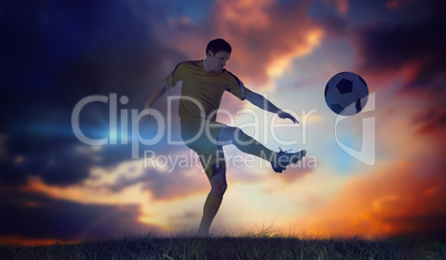 Composite image of football player in yellow kicking