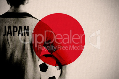 Composite image of japan football player holding ball