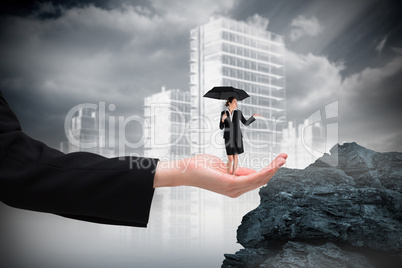 Composite image of young businesswoman holding umbrella in hand