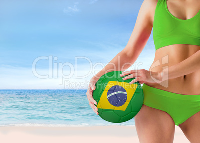 Composite image of fit girl in green bikini holding brasil ball