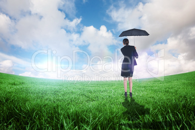 Composite image of young businesswoman holding umbrella