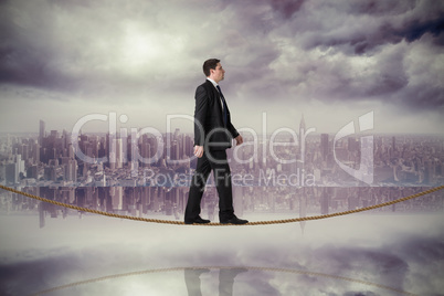 Composite image of handsome businessman stepping on tightrope