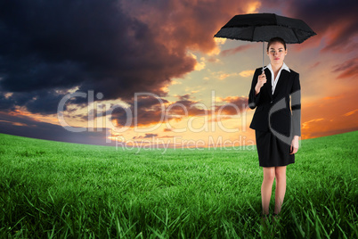 Composite image of young businesswoman holding umbrella