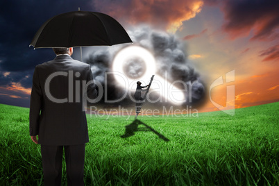 Composite image of mature businessman holding an umbrella