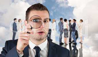 Composite image of businessman looking through magnifying glass