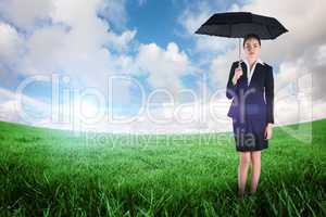 Composite image of young businesswoman holding umbrella