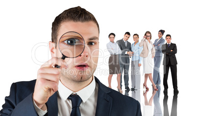 Composite image of businessman looking through magnifying glass