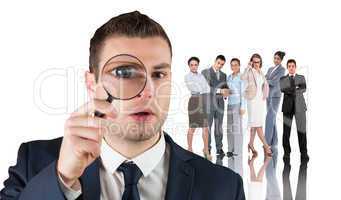 Composite image of businessman looking through magnifying glass