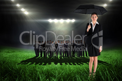 Composite image of young businesswoman holding umbrella