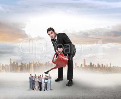 Composite image of businessman watering tiny business team