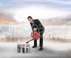 Composite image of businessman watering tiny business team