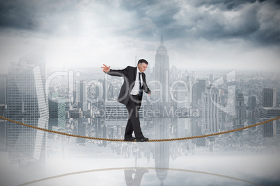 Composite image of mature businessman doing a balancing act on t