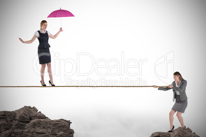 Young business woman pulling a tightrope for businesswoman