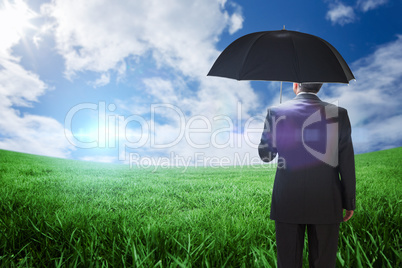 Composite image of mature businessman holding an umbrella