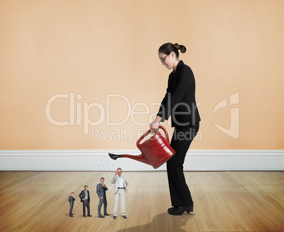 Composite image of businesswoman watering tiny business team