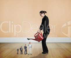 Composite image of businesswoman watering tiny business team