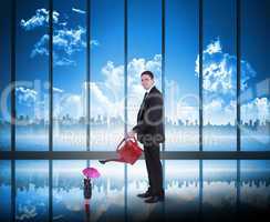 Composite image of businessman watering tiny businesswoman
