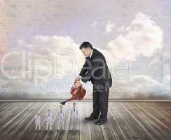 Composite image of mature businessman watering tiny businessman