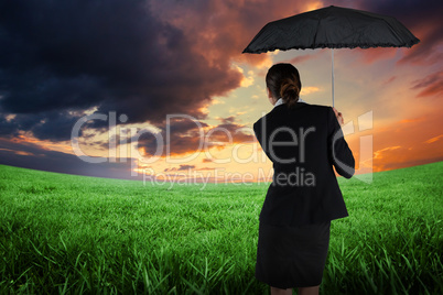 Composite image of young businesswoman holding umbrella