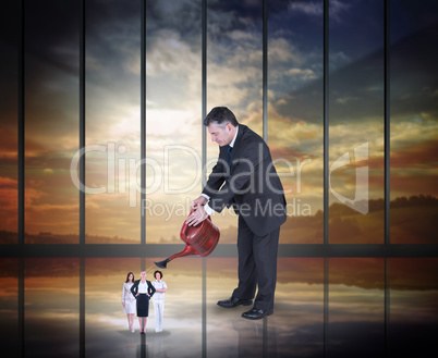 Composite image of mature businessman watering tiny business wom