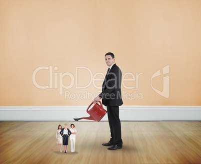 Composite image of businessman watering tiny businesswomen