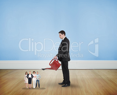 Composite image of businessman watering tiny business team