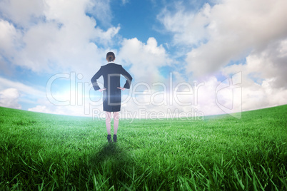 Composite image of young businesswoman standing with hands on hi