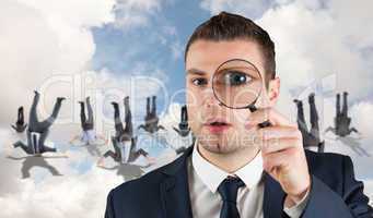 Composite image of businessman looking through magnifying glass