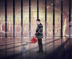 Composite image of businessman watering tiny businessman