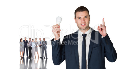 Composite image of businessman holding light bulb and pointing