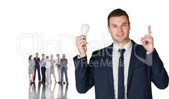 Composite image of businessman holding light bulb and pointing