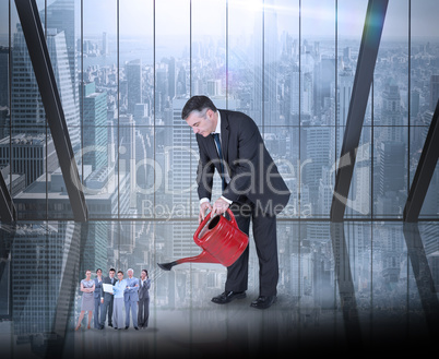 Composite image of mature businessman watering tiny business tea