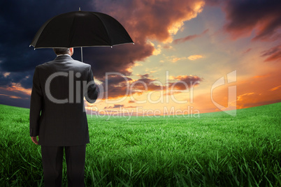 Composite image of mature businessman holding an umbrella