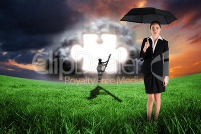 Composite image of young businesswoman holding umbrella