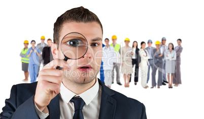 Composite image of businessman looking through magnifying glass