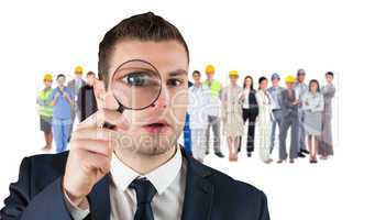 Composite image of businessman looking through magnifying glass