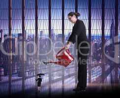 Composite image of businesswoman watering tiny business woman