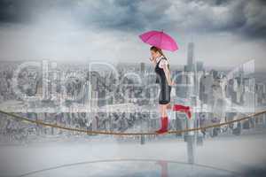 Composite image of pretty redhead businesswoman holding umbrella