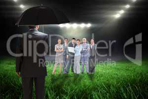 Composite image of mature businessman holding an umbrella