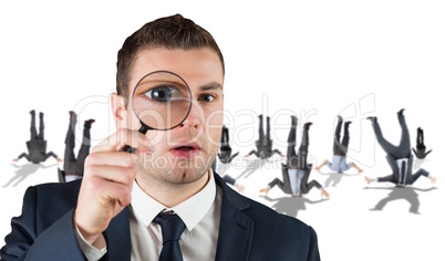 Composite image of businessman looking through magnifying glass