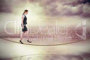 Composite image of redhead businesswoman stepping on tightrope