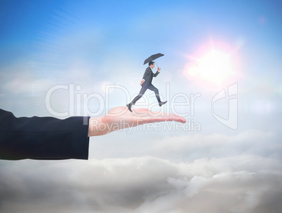 Composite image of businessman jumping holding an umbrella