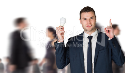 Composite image of businessman holding light bulb and pointing